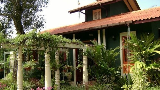 A house with a green exterior, a red roof, and a white pergola covered with plants. - Marakolliya Stay, 2BR Residential Holiday Bungalow (Hambantota)