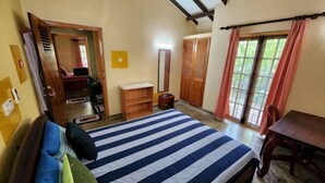 A bedroom with a bed, a wooden table, a wardrobe, and a door leading to another room. - Marakolliya Stay, 2BR Residential Holiday Bungalow (Hambantota)