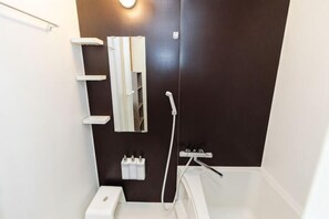 Ein Badezimmer mit Toilette, Spiegel, Handtuchhalter und Dusche.