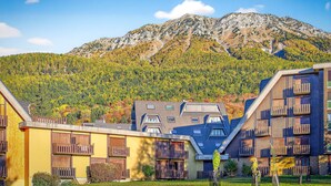 Un edificio moderno con balcones, con montañas al fondo.
