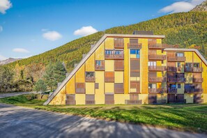 A multi-story building with balconies, set against a mountainous backdrop. - Cosy and Bright in Montclar, Alpes-de-Haute-Provence (Montclar)