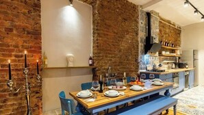 A dining area with a brick wall, a wooden table set for four, and a bench. - Ganbaru Tours - Private Triplex&Duplex (Istanbul)