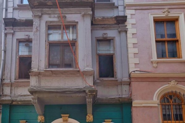 A building facade with classical architectural features, including a green door and a window with a wooden frame. - Ganbaru Tours - Private Triplex&Duplex (Istanbul)