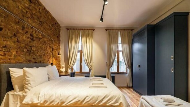A bedroom with a large bed, a wardrobe, and a stone wall. - Ganbaru Tours - Private Triplex&Duplex (Istanbul)