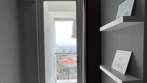 A modern interior with a view through a glass door to an outdoor balcony. - 2 BR ANDERSON 25floor above pakuwon mall the biggest shopping center (Wiyung)