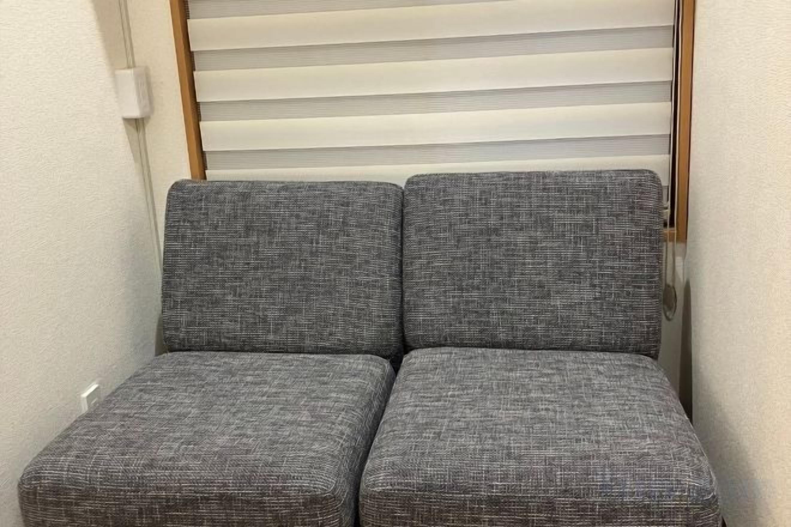 A corner seating area with two grey upholstered chairs.