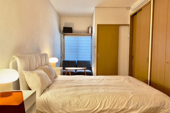 A hotel room with a bed, bedside table, lamp, and a view of a balcony.