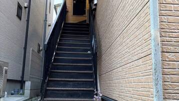 Una escalera estrecha que sube a un nivel superior, flanqueada por muros de ladrillo, con una puerta en la parte superior.