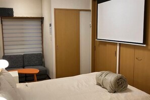 A hotel room with a bed, a small table, a sofa, a TV, and a wardrobe. - CUBE STAY KITA-TOKYO (Tokyo)