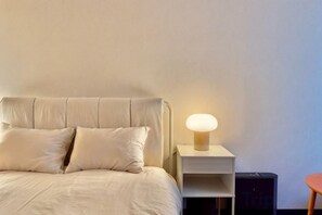 A bed with a headboard, a bedside lamp, and a nightstand. - CUBE STAY KITA-TOKYO (Tokyo)