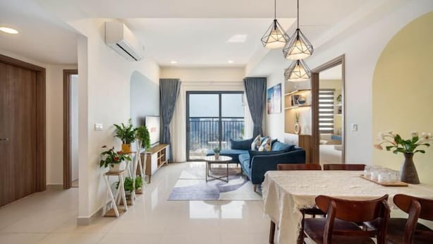 A modern living room with a sofa, dining table, and chairs. There is a balcony with a view, and the room has a large window. - Soho Residence-Tony Apartment (Ho Chi Minh City)