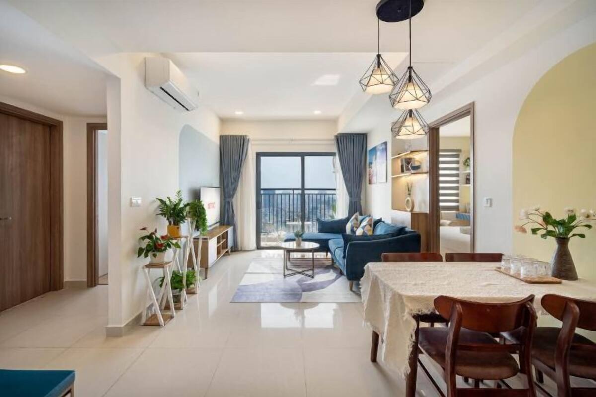 Un salon moderne avec un canapé, une table à manger et des chaises. Il y a un balcon avec vue, et la pièce est dotée d’une grande fenêtre.