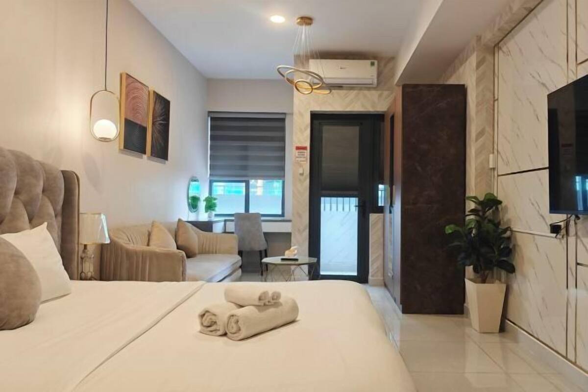 Une chambre d’hôtel moderne avec un grand lit, un canapé, une petite table et un téléviseur.