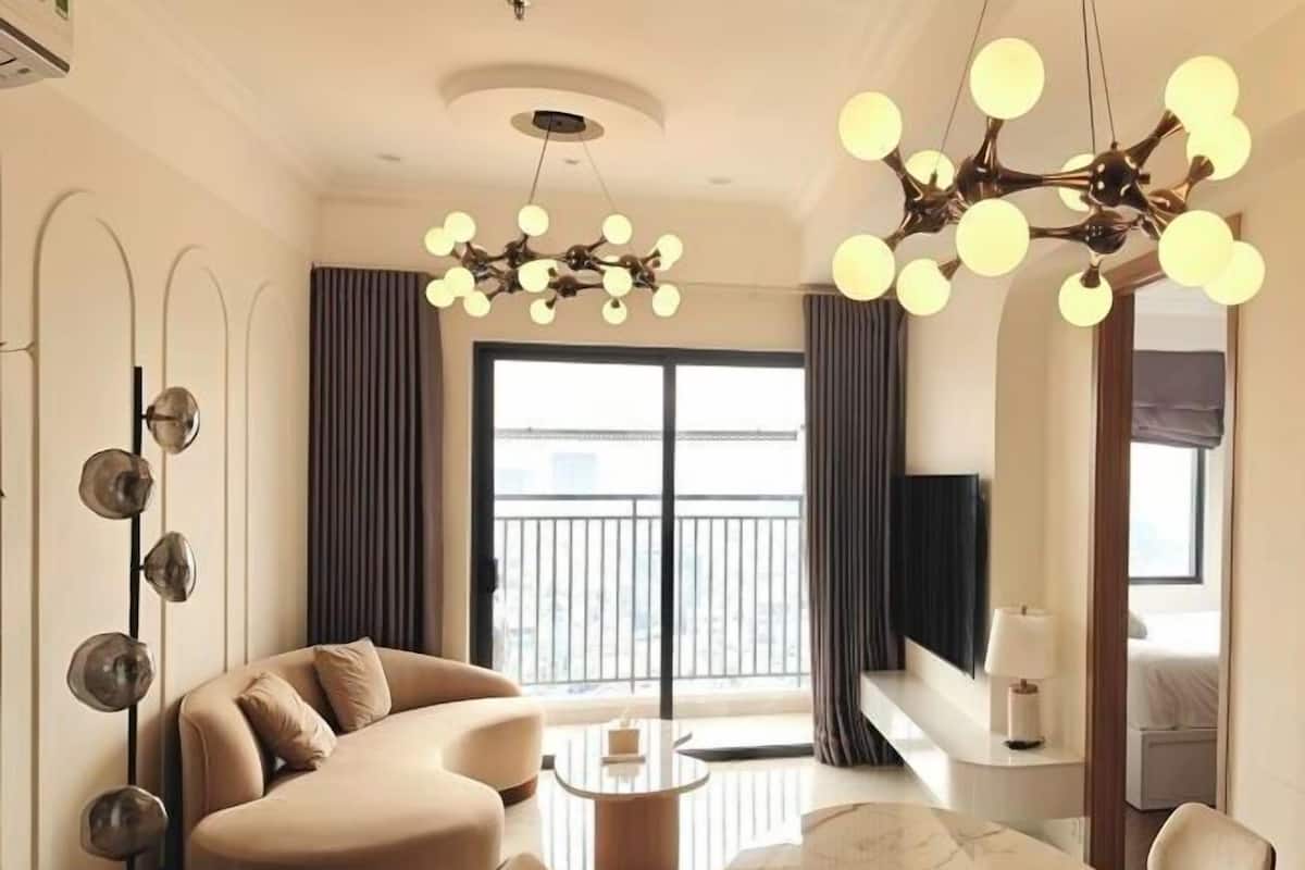 Une chambre d’hôtel moderne, dotée d’un canapé, d’une petite table, d’un lustre et d’un balcon offrant une vue agréable.