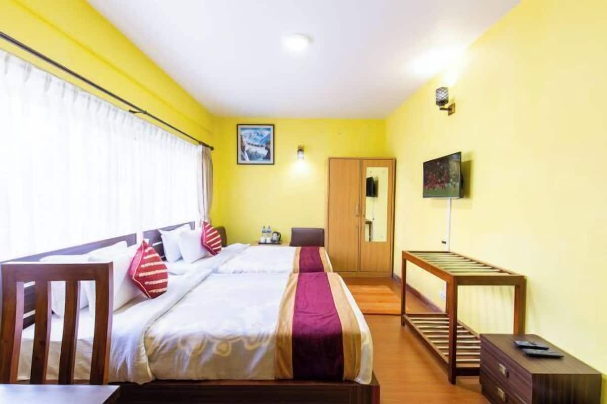 A hotel room with a bed, a desk, a chair, a TV, and a wardrobe.