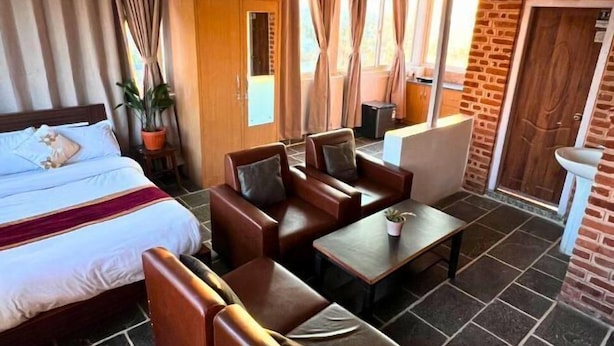 A hotel room with a bed, a sofa, a table, and a potted plant. - Deepjyoti Inn (Kathmandu)