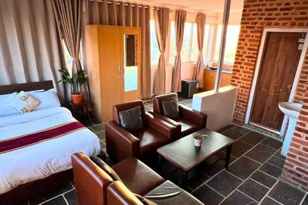 A hotel room with a bed, a sofa, a table, and a potted plant.