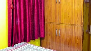 A room with a bed, a wooden wardrobe with two doors, and a red curtain. - Deepjyoti Inn (Kathmandu)