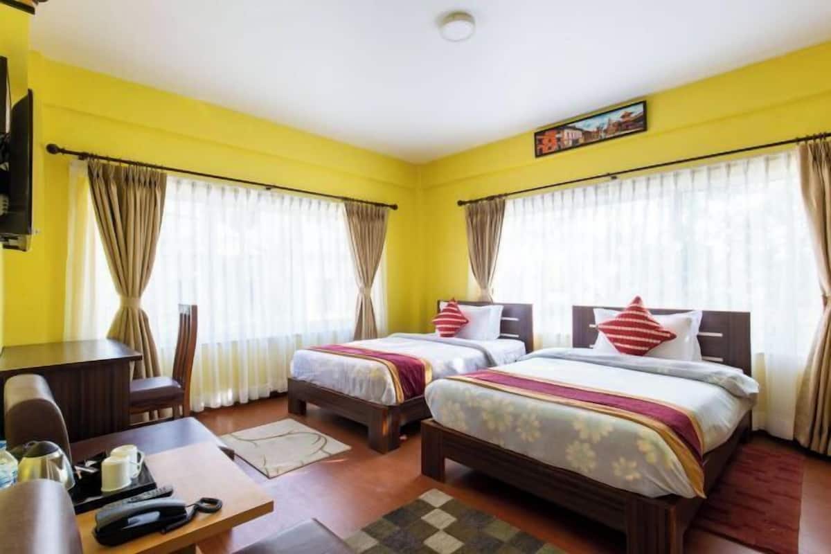 A hotel room with two beds, a desk, and a chair.