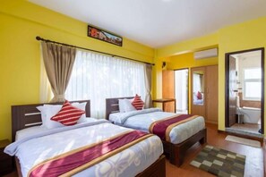 A hotel room with two beds, a bathroom, and a view of the outside. - Deepjyoti Inn (Kathmandu)