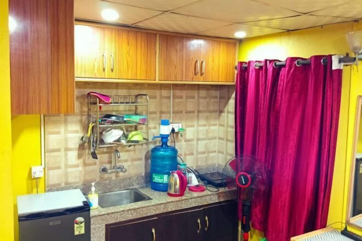 A kitchen with wooden cabinets, a sink, a gas stove, and a red curtain.