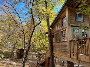 Une cabane en bois dotée d’une terrasse, entourée d’arbres aux feuilles d’automne.