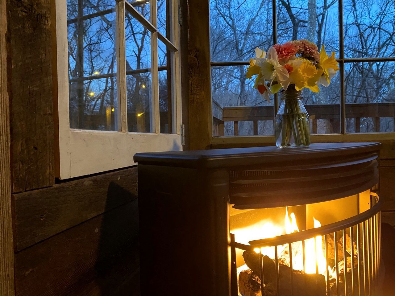 Una chimenea con un florero de flores sobre un alféizar.