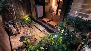 A cozy outdoor seating area with a wooden bench and a small table, surrounded by plants and a stone pathway. - Kyokoi Kiyomizu Gojo (Kyoto)