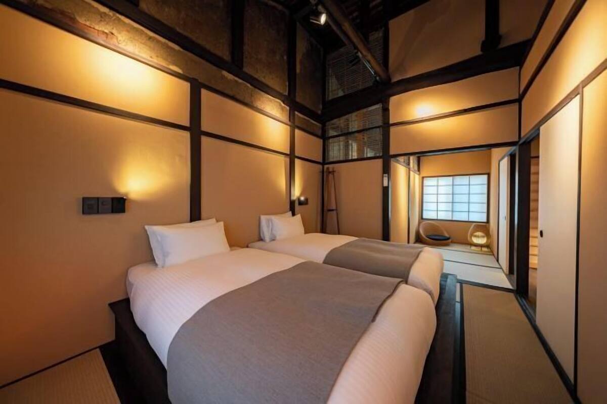 Une chambre d’hôtel avec deux lits, un intérieur de style japonais traditionnel et une vue sur une pièce de style japonais traditionnel.