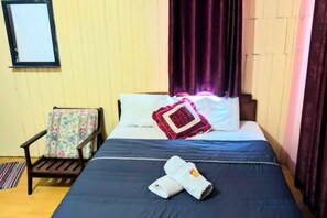 A bed with a dark blue bedspread, a red and white pillow, and a folded towel on the bed. - Marang Guesthouse Resort (Rusila)