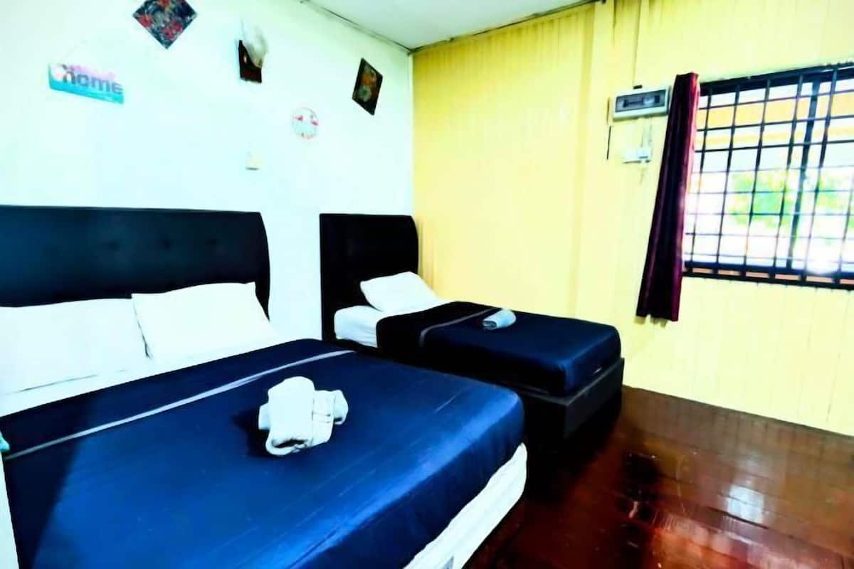 A room with two beds, a window with bars, and a yellow wall.