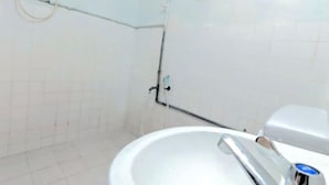A bathroom with white tiled walls, a white sink with a chrome faucet, and a white toilet. - Marang Guesthouse Resort (Rusila)