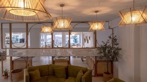 A modern interior with a curved sofa, wicker furniture, and large woven ceiling lamps. - Arkadia Hotel (Arkadii)