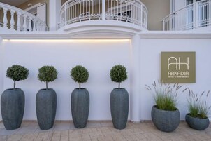Zona de recepción de hotel con diseño moderno, que incluye una pared blanca, un mostrador de recepción y un cartel.