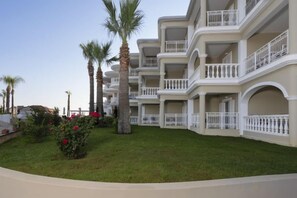 A hotel with multiple balconies, a well-maintained lawn, and palm trees. - Arkadia Hotel (Arkadii)