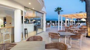 An outdoor dining area with wicker furniture and a bar. - Arkadia Hotel (Arkadii)