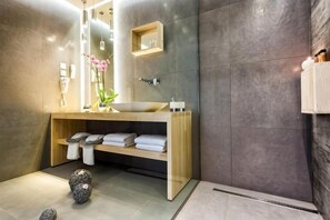 A modern bathroom with a wooden vanity, a mirror, a towel rack, and a shower area. - Arkadia Hotel (Arkadii)