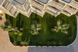 A multi-story hotel with balconies, a well-maintained lawn, and palm trees. - Arkadia Hotel (Arkadii)