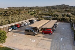 A parking lot with cars and a covered area, surrounded by hilly terrain. - Arkadia Hotel (Arkadii)