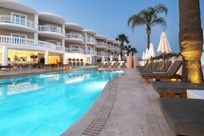 A swimming pool with lounge chairs and umbrellas, a building with balconies, and palm trees. - Arkadia Hotel (Arkadii)