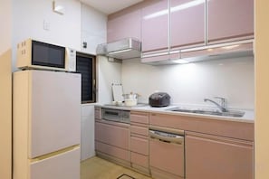 A compact kitchen with a microwave, stove, sink, and cabinets. - AOU･KOUCHA (Osaka)