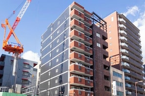 A multi-story building with a crane in the foreground, suggesting ongoing construction or maintenance. - AOU･KOUCHA (Osaka)
