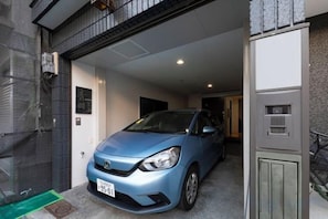Un cotxe blau estacionat a un garatge amb una porta que dona a una habitació.