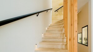 A staircase with a wooden handrail and carpeted steps leading to a landing.