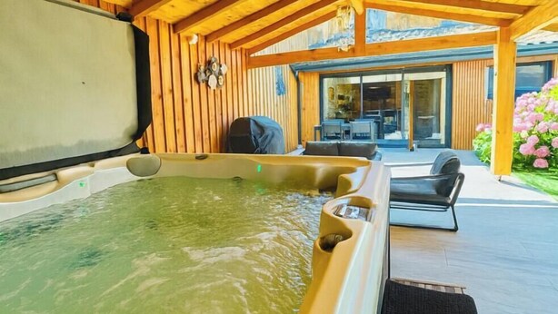 A hot tub in a wooden cabin with a patio area and outdoor seating.