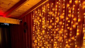 A hot tub with a wooden wall and string lights.