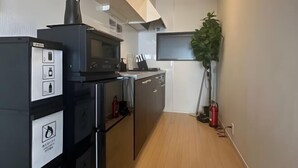 Una cucina compatta con forno a microonde, forno e lavastoviglie, un piccolo lavandino e una pianta in vaso.