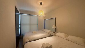 Una camera d'albergo con due letti, un comodino, una lampada e una luce a soffitto.