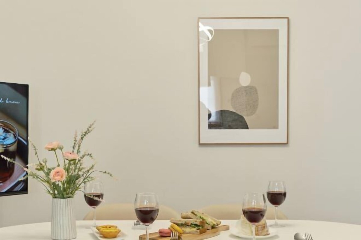 A dining table with a vase of flowers, a sandwich, and wine glasses.