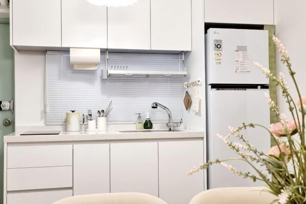 A modern kitchen with white cabinets, a sink, and a refrigerator. - Haru Stay/Queen Bed 3/Seoul Station. Hongdae. Gangnam 30 minutes/Subway Station 7 minutes (Seoul)